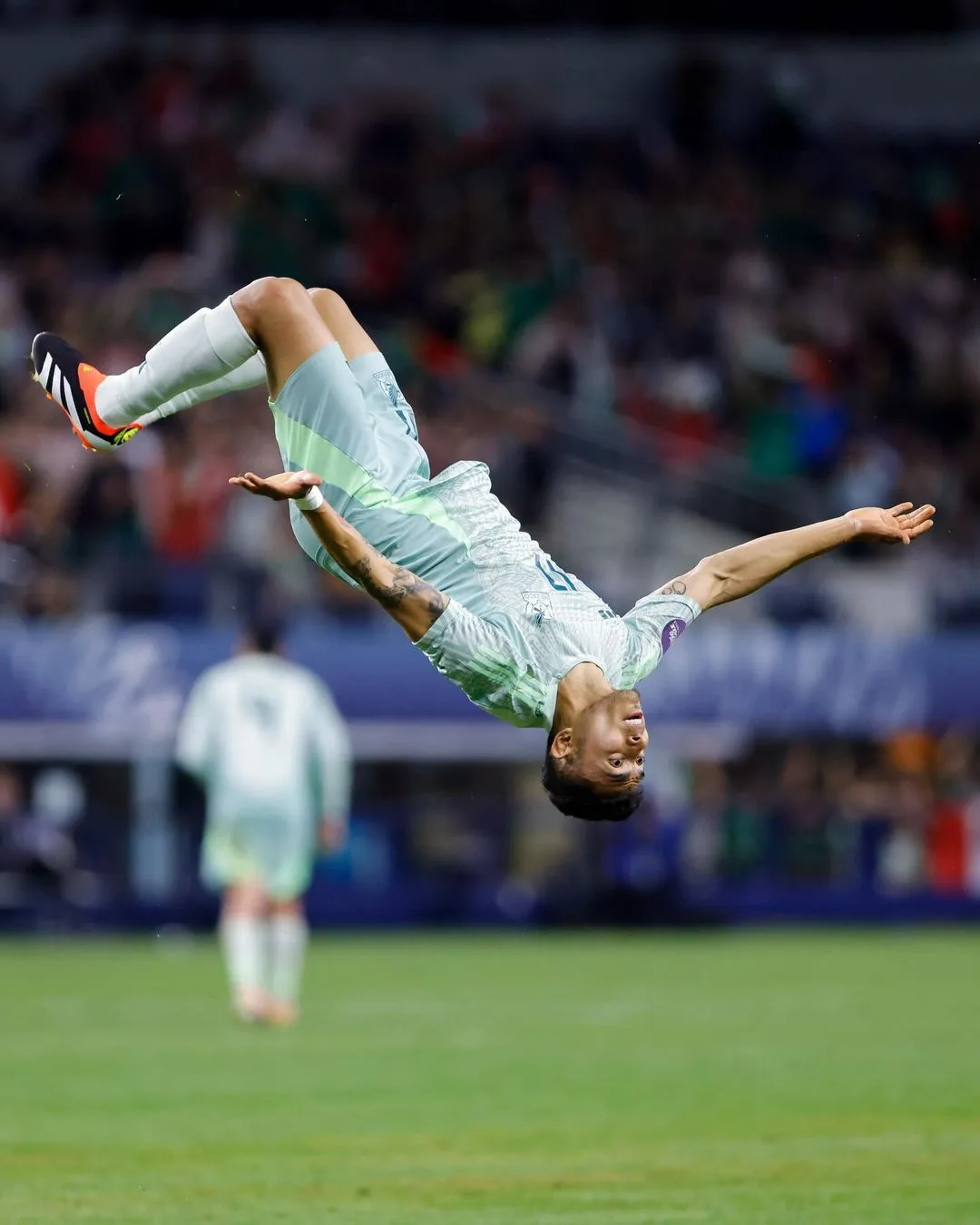 Joueur en maillot blanc en plein salto arrière pour fêter un but